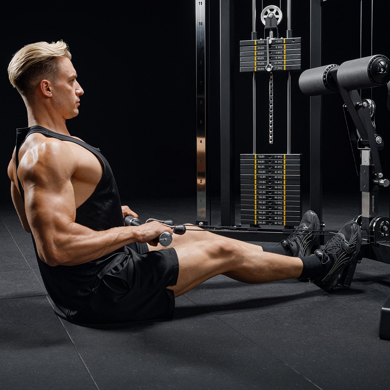 A user performing seated rows using the low pulley system on the Mikolo FALCON 2.0 Functional Trainer in a home gym