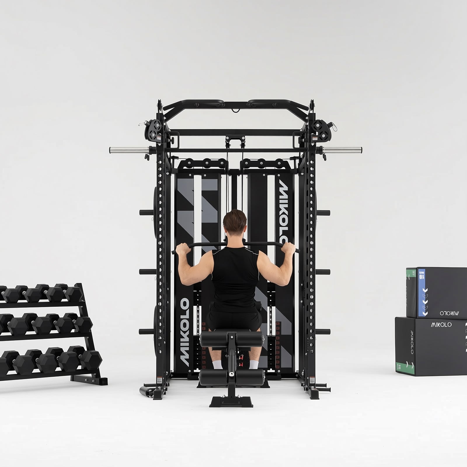 Man performing lat pulldowns on a black Mikolo Smith machine and functional trainer with a dumbbell rack to the left