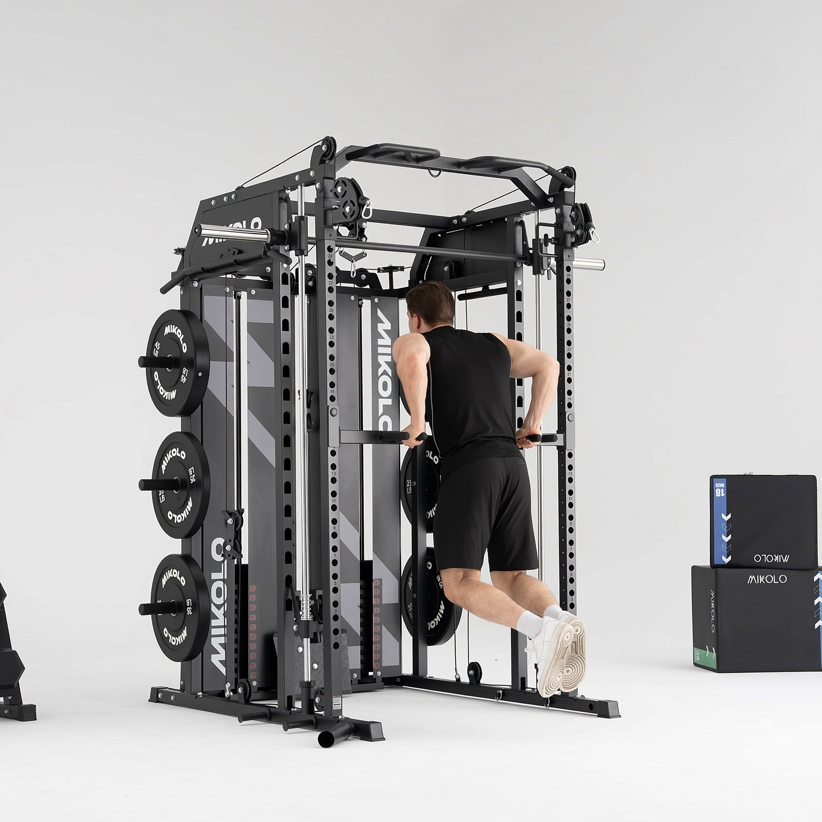 A man performs dips on a black MIKOLO Smith machine and functional trainer with weight plates loaded on the side
