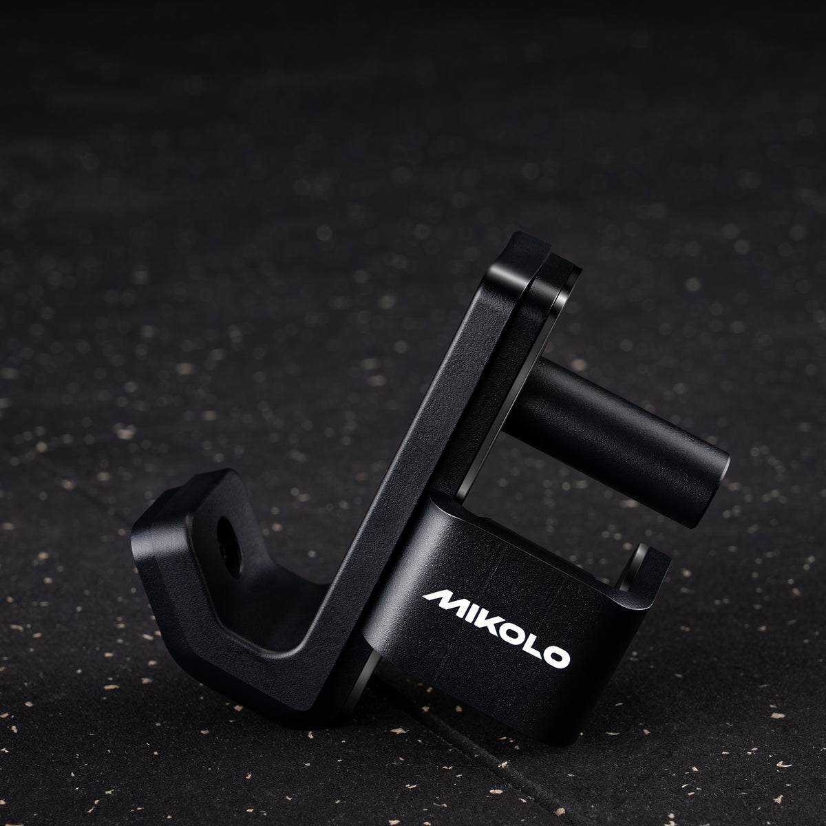 Black Mikolo J-hooks with a U-shaped bar rest and cylindrical handle on a dark speckled floor
