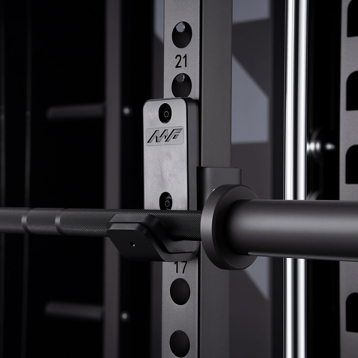 Black barbell resting in a silver J-hook attachment with MF logo on a black power rack upright showing numbered holes