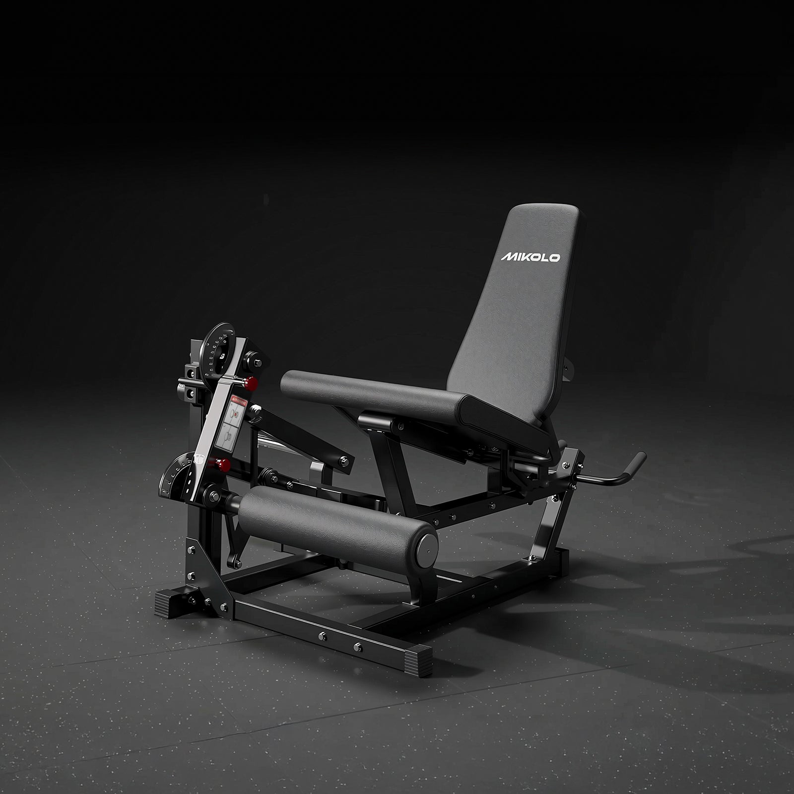 Black and grey Mikolo leg extension machine with a padded seat, backrest, and cylindrical leg roller on a dark surface