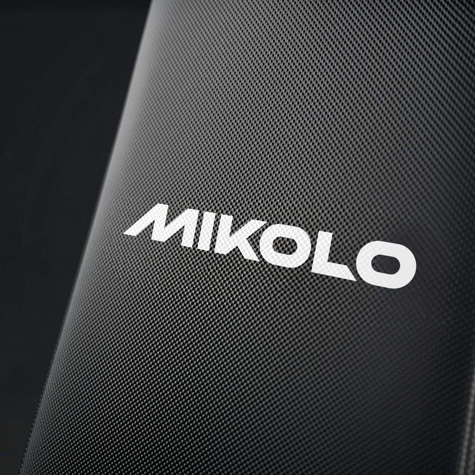 White Mikolo logo on the black textured upholstery of a fitness machine