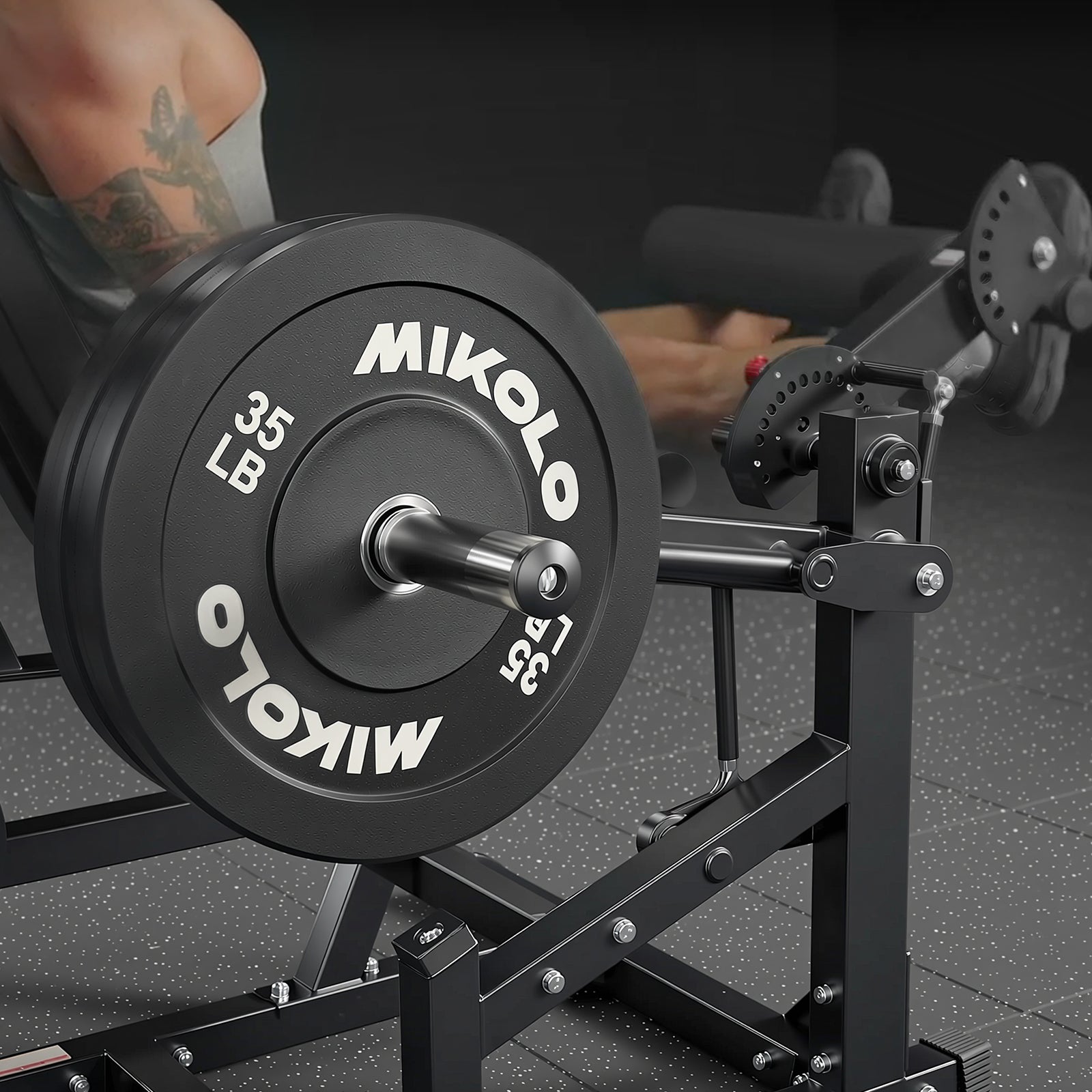 Black 35 lb Mikolo weight plate on a leg curl machine with a user's tattooed leg in the background
