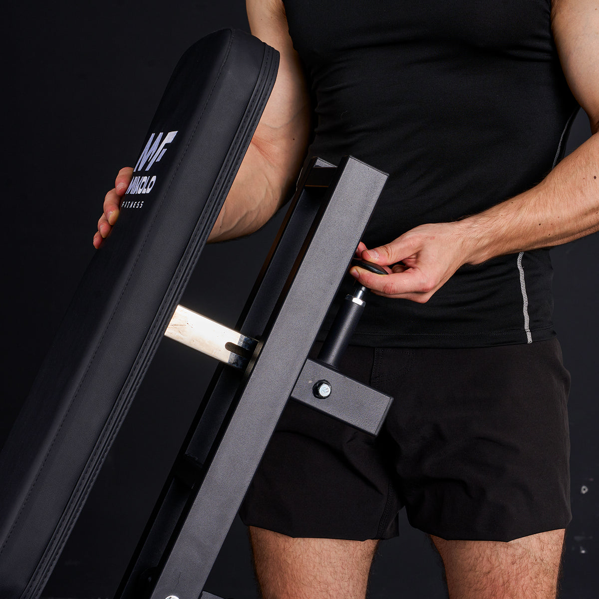Person in black athletic wear adjusting the backrest of a Mikolo Fitness leg extension machine by turning a frame knob
