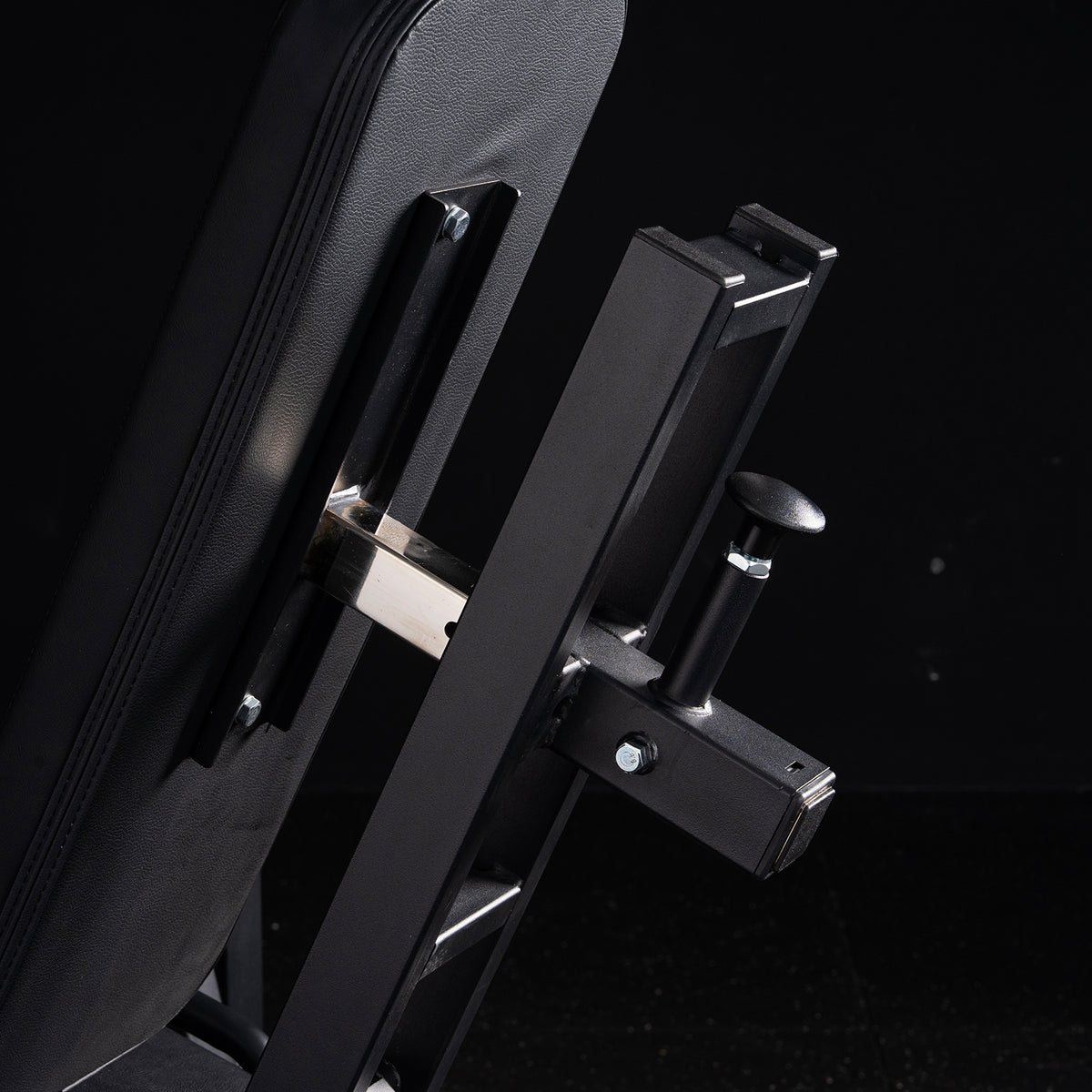 Black padded backrest and metal adjustment mechanism with a locking knob on a leg exercise machine frame