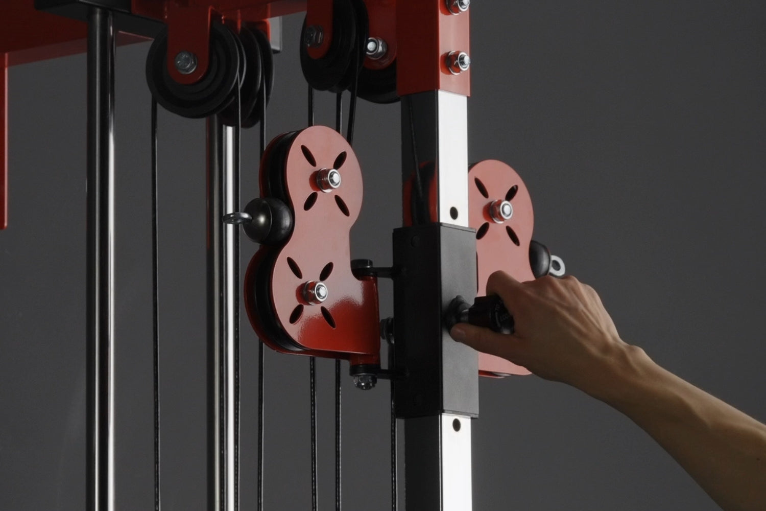 Close-up of the height-adjustable red pulley carriage with quick pin lock on the Mikolo Plate Loaded Pulley Tower G3