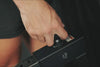 Close-up of a hand turning a black adjustment knob on a metal frame labeled with the number 1